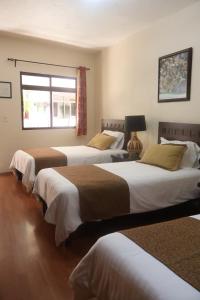 three beds in a room with a window at Hotel Plaza San Carlos in Xicotepec de Juárez +93 photos