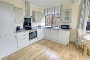 a kitchen with white cabinets and a wooden floor at 1 Bed in Seaton oc-mbsov in Seaton
