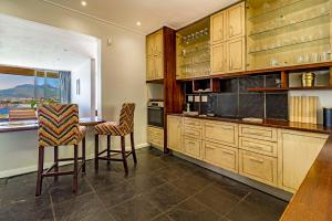 a kitchen with wooden cabinets and a table and chairs at 5 Suikerbossie in Gordonʼs Bay +18 photos