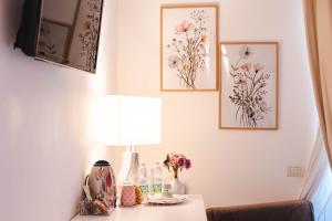 Ein Zimmer mit einem Tisch, auf dem eine Lampe steht, und Bildern an der Wand. in der Unterkunft Dimora Francesca in Conversano