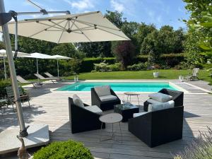 a patio with chairs and an umbrella next to a pool at Au Milieu des Haras in Saint-Pierre-Azif