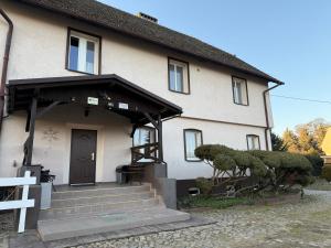 a white house with a black door and some trees at Noclegi pracownicze Mitarbeiterunterkünfte Employee accommodation in Chojna