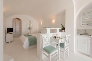 a white bedroom with a bed and a table at Anastasis Apartments and Spa in Imerovigli