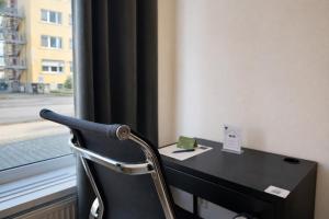 a black desk with a chair next to a window at FRAME by Tendo Stay - Comfort Housing in Falkensee