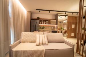 a living room with a couch and a kitchen at Jurerê Sol&Mar Temporada in Florianópolis +39 photos