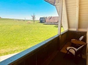 a porch with two chairs and a table and a field at Badischhaus am Waldrand & Weitblick in Herrischried