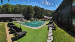 an outdoor swimming pool with lounge chairs and umbrellas at Hotel Nevados de Chillan in Nevados de Chillan