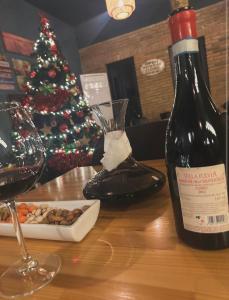 Eine Flasche Wein auf einem Tisch neben einem Weihnachtsbaum in der Unterkunft Hotel Muja in Rinas