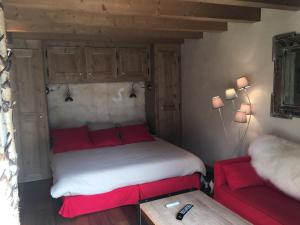 una camera con un letto e un divano rosso di Chalet Mine de rien a Megève