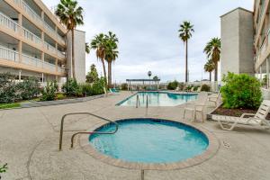 a swimming pool in a resort with palm trees at Steps to North Beach: Gem w/ Ocean-View Balcony! in Corpus Christi