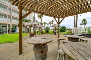 a patio with wooden tables and chairs and a building at Steps to North Beach: Gem w/ Ocean-View Balcony! in Corpus Christi