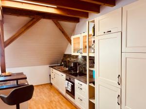 a kitchen with white cabinets and a black chair at Badischhaus am Waldrand & Weitblick in Herrischried
