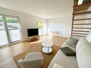 a living room with a white couch and a tv at Feigenterrasse beim Semmering - Tiny House in Schlagl