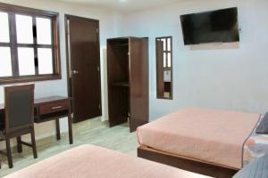 a bedroom with two beds and a desk and a television at Hotel ESTRELLA in Zacatlán