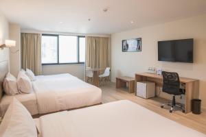 ein Hotelzimmer mit zwei Betten und einem Schreibtisch in der Unterkunft Unipark by Oro Verde Hotels in Guayaquil