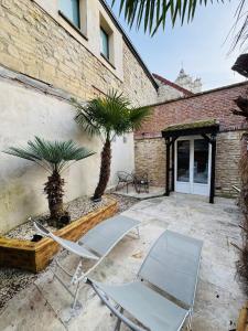 two chairs and palm trees in front of a building at Le Cupidon & Spa in Pont-Sainte-Maxence