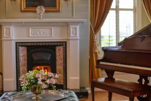 a living room with a piano and a vase of flowers at The Allen House in Ridgefield