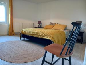 a bedroom with a bed and a wooden chair at La maison in Cruviers-Lascours