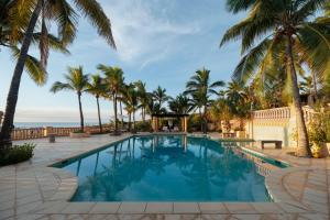 a pool with palm trees and the ocean in the background at La Valise Los Cabos, Member of Small Luxury Hotels in Boca de la Vinorama