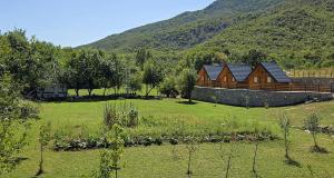a wooden cabin in a field with a mountain at Etno Lug - Village in Bogetići