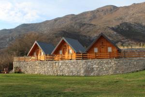 a row of wooden cabins with mountains in the background at Etno Lug - Village in Bogetići +11 photos