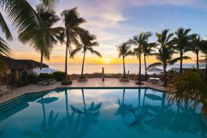 a pool with palm trees and the ocean at sunset at La Valise Los Cabos, Member of Small Luxury Hotels in Boca de la Vinorama