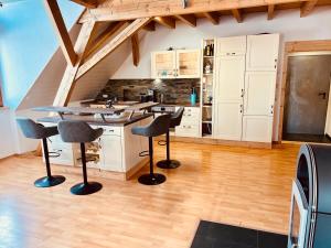 a kitchen with white cabinets and bar stools at Badischhaus am Waldrand & Weitblick in Herrischried