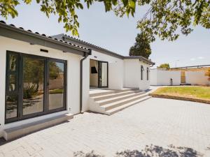 a white house with large windows and a patio at Catalyst Guest House in Cape Town
