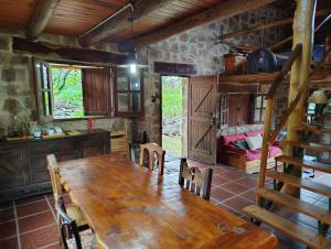 a dining room with a wooden table and a bed at Stone Cabin, PETRA HAUS in Cuesta Blanca