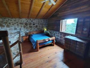 a bedroom with a bed in a log cabin at Stone Cabin, PETRA HAUS in Cuesta Blanca