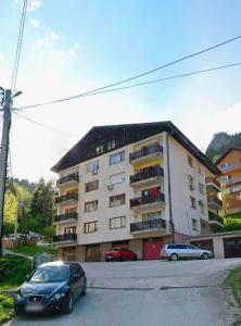 a apartment building with cars parked in front of it at Apartman Daki in Vareš