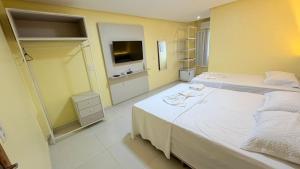 a hotel room with two beds and a television at Hotel Diamond Exclusive in Oiapoque