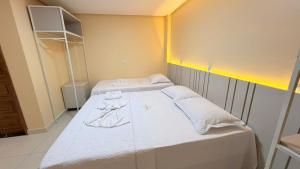 a bedroom with two beds with white sheets and towels at Hotel Diamond Exclusive in Oiapoque