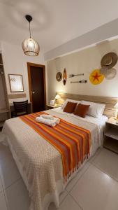 a bedroom with a large bed with an orange and white blanket at Pousada Mar da Vila in Cabo Frio +28 photos