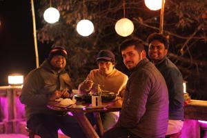 a group of men sitting at a table at night at Trippers hostel in Darjeeling