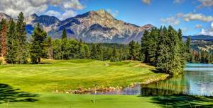 a golf course with a lake and mountains in the background at Best Western Mountainview Inn in Golden