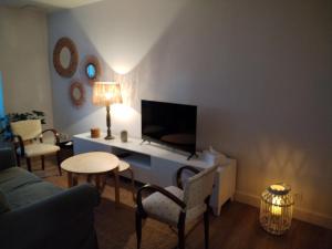 ein Wohnzimmer mit Fernseher, Tisch und Stühlen in der Unterkunft Le3cent85 in Saint-Germain-Laval