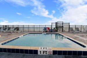 a pool on a patio with chairs and a fence at Outrigger Beach Club Resort by CoolVacay in Ormond Beach
