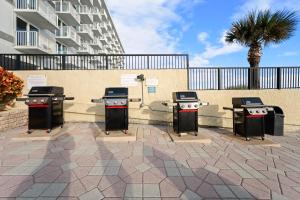a group of four bbq grills on a patio at Outrigger Beach Club Resort by CoolVacay in Ormond Beach