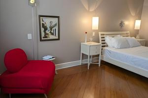 a bedroom with a bed and a red chair at SHB - Beach House with Air Conditioning in Santos
