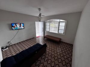 a living room with a couch and a flat screen tv at Casa de praia in Mongaguá