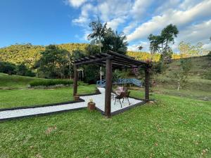 a gazebo with a bench in a yard at Sítio Monte Frederico in Nova Trento