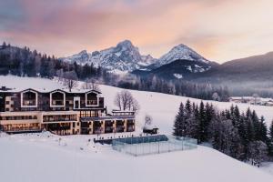 a resort in the snow with mountains in the background at Hotel Neubergerhof in Filzmoos