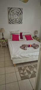 a bedroom with a bed with pink pillows at Au zamana in Le Robert