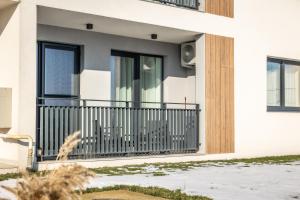 a white house with a balcony with black windows at Smarald Apartment in Satu Mare