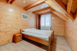 a bed in a wooden room with a window at ViiLa Munte Călimani in Topliţa +46 photos