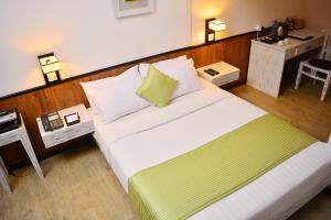a bedroom with a large bed with green and white pillows at Unique Cottages in Nuwara Eliya