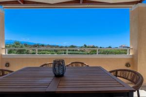 a wooden table with chairs on a porch with a large window at Koralia's Villas in Chorafakia