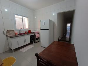 a kitchen with a refrigerator and a table in it at Aconchego em Bertioga in Bertioga +6 photos