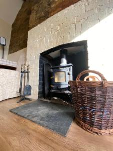 a brick fireplace with a wicker basket next to it at Forge Cottage, Cosy Couples Retreat in the Devon Countryside, Indoor Pool, Tennis Court and Tarka Trail Access in Merton
